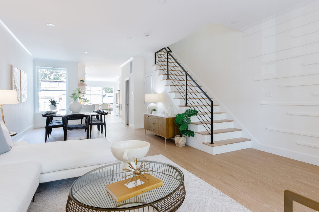A view through the front floor of this open concept townhouse, including the living room, dining room, staircase and the kitchen in the back.