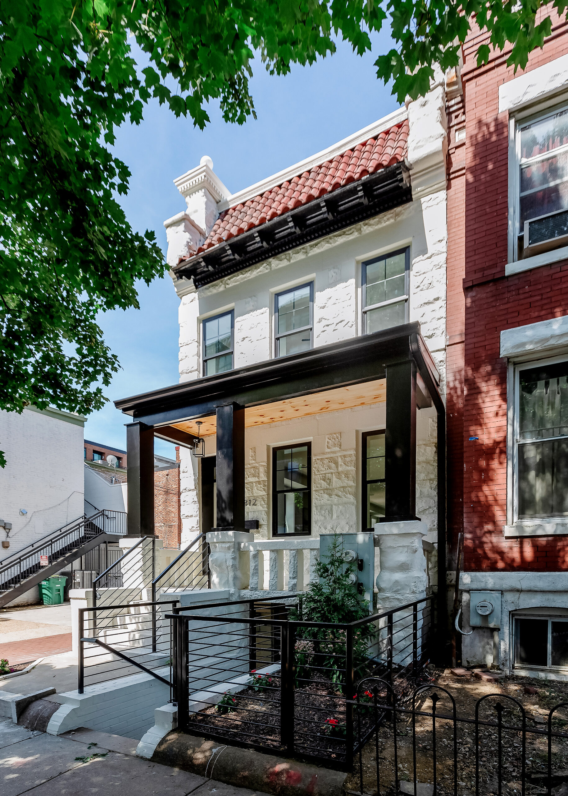 Front exterior of a white renovated DC townhouse with historic brick details and modern third-floor addition